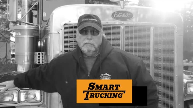 Truck Driver standing by the grill of his Peterbilt truck