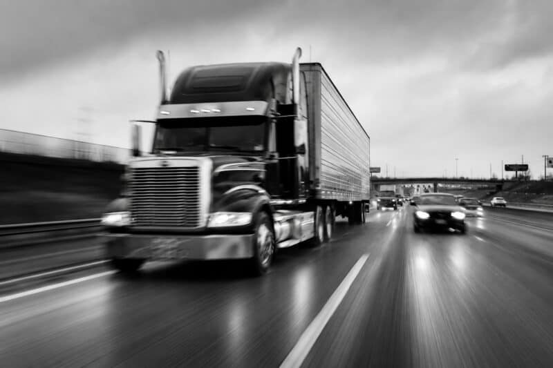 Semi truck and trailer speeding on wet highway